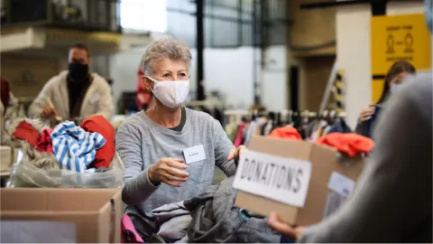 Photo of a volunteer wearing a protective face mask collecting donations